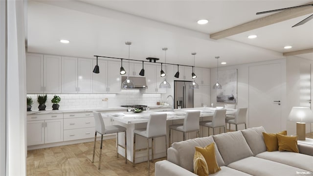 kitchen with pendant lighting, stainless steel fridge, an island with sink, white cabinets, and beamed ceiling