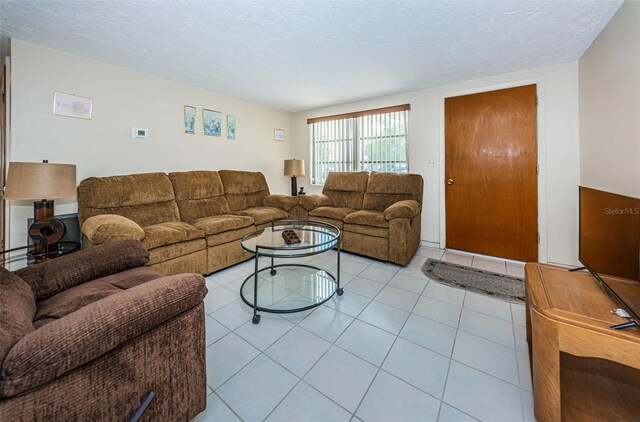 living room with a textured ceiling and light tile flooring