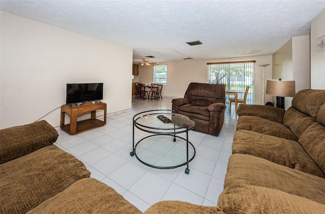 living room featuring light tile floors, ceiling fan, and a textured ceiling