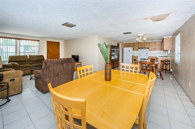 tiled dining space with a textured ceiling, ceiling fan, and sink