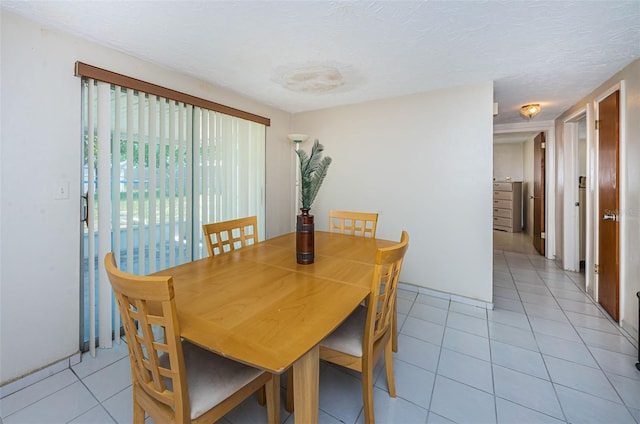 dining space featuring light tile floors and a textured ceiling