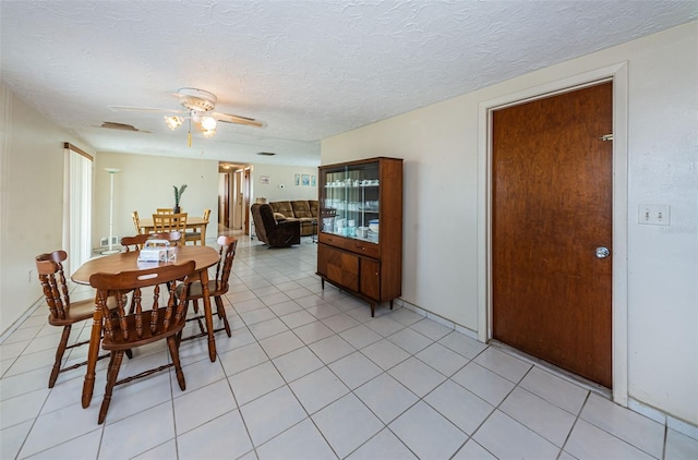 dining room with a textured ceiling, ceiling fan, and light tile floors