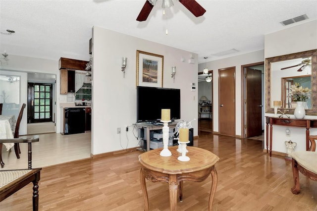 living room with light hardwood / wood-style flooring, a textured ceiling, and ceiling fan