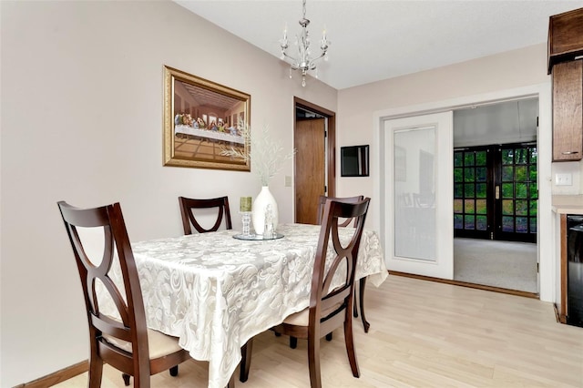 dining area featuring a notable chandelier, french doors, and light wood-type flooring