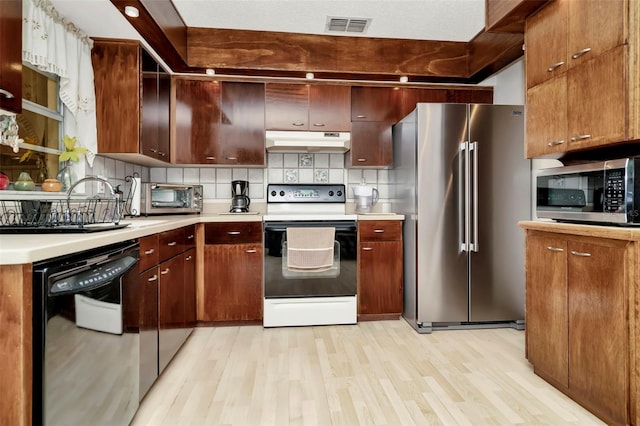 kitchen with decorative backsplash, light hardwood / wood-style flooring, and stainless steel appliances