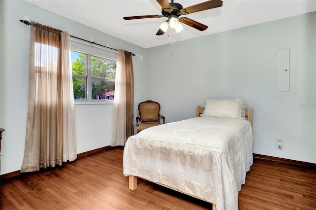 bedroom with wood-type flooring, electric panel, and ceiling fan