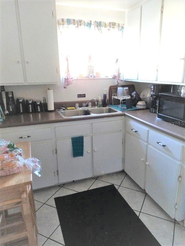 kitchen featuring white cabinetry, sink, and light tile patterned floors