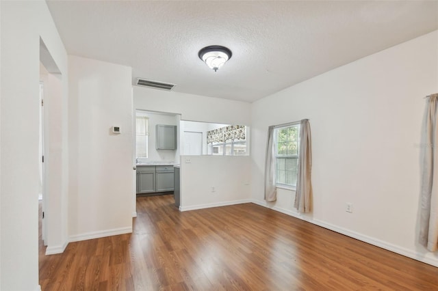 unfurnished room with a textured ceiling and wood-type flooring