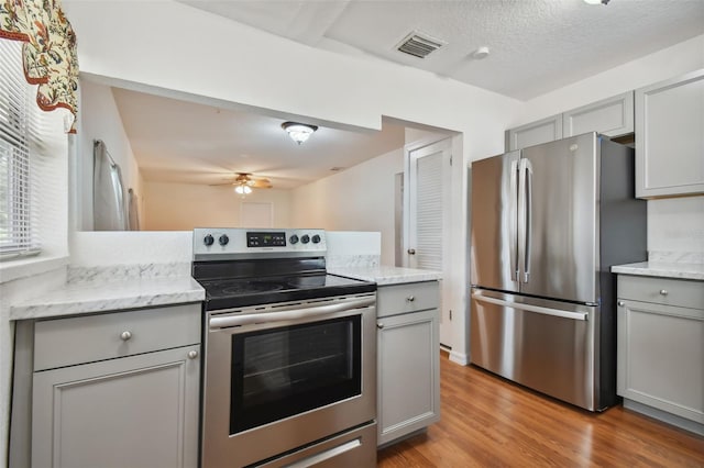 kitchen with light hardwood / wood-style floors, ceiling fan, stainless steel appliances, and gray cabinetry