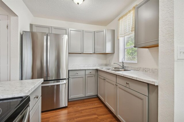 kitchen with range, gray cabinetry, stainless steel fridge, sink, and dark hardwood / wood-style floors