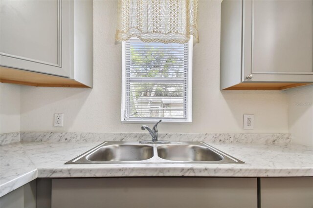 kitchen with gray cabinets, light stone countertops, and sink