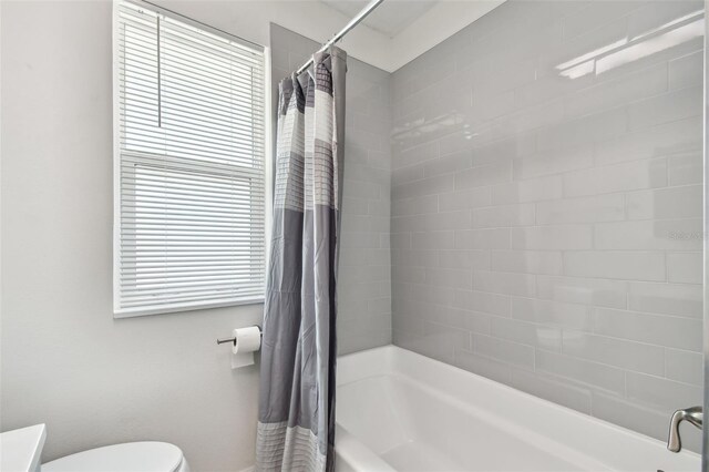 bathroom with shower / bath combo with shower curtain and toilet