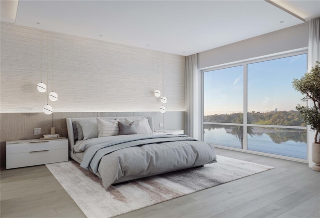 bedroom with light hardwood / wood-style flooring and a water view