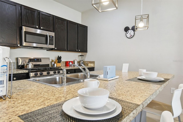 kitchen featuring dark brown cabinets, stainless steel appliances, sink, hanging light fixtures, and a breakfast bar area