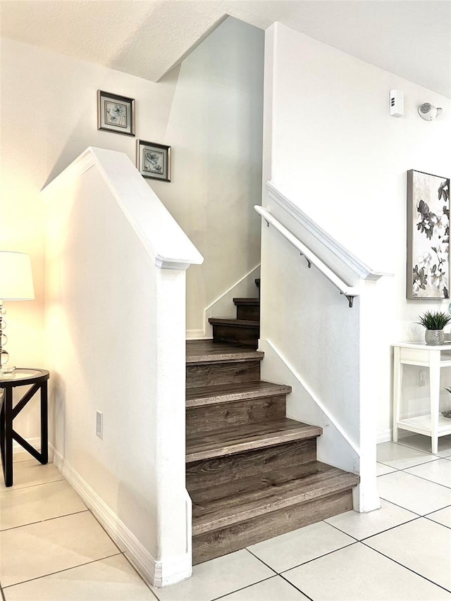 stairway featuring a textured ceiling and tile patterned floors