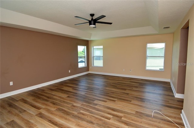 spare room with hardwood / wood-style floors, a textured ceiling, ceiling fan, and a raised ceiling