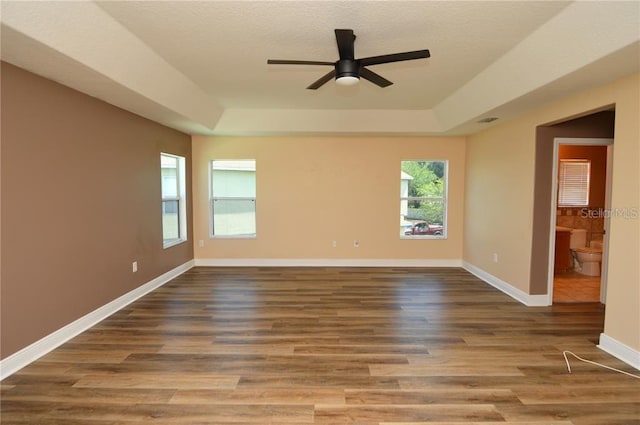 spare room with hardwood / wood-style floors, a tray ceiling, and ceiling fan