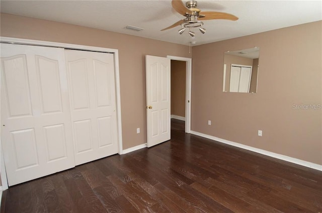 unfurnished bedroom featuring ceiling fan, a closet, and dark wood-type flooring