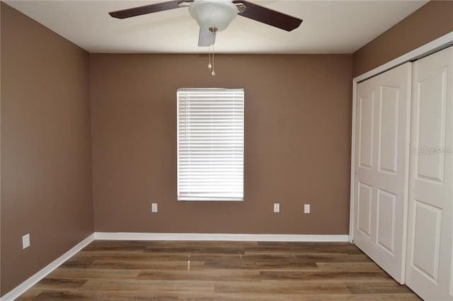 unfurnished bedroom featuring dark hardwood / wood-style flooring, ceiling fan, and multiple windows