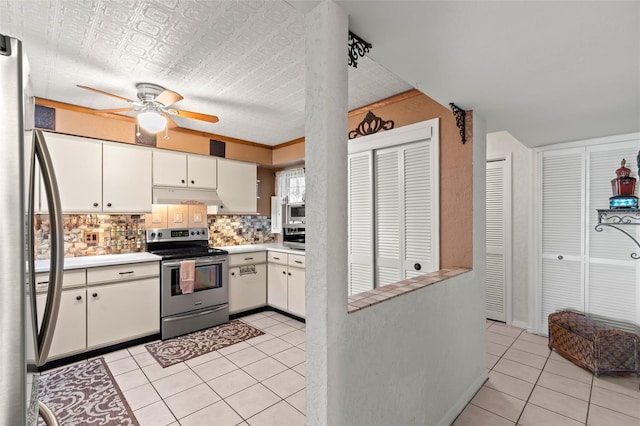 kitchen with white cabinets, stainless steel appliances, backsplash, light tile patterned floors, and ceiling fan