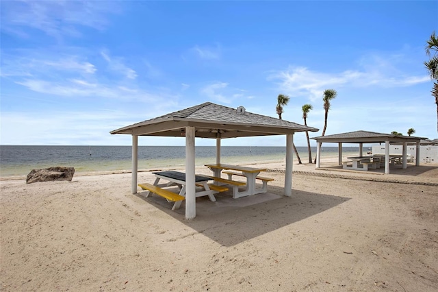 view of home's community with a gazebo, a water view, and a beach view