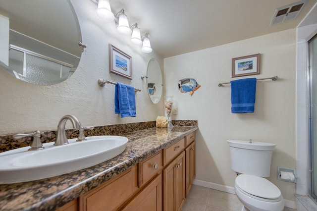 bathroom featuring tile patterned floors, toilet, a shower with shower door, and vanity