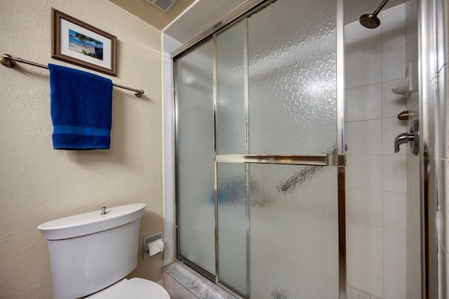 bathroom featuring a shower with shower door and toilet