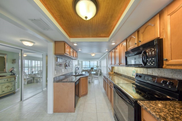 kitchen featuring light tile patterned flooring, sink, black appliances, a raised ceiling, and backsplash