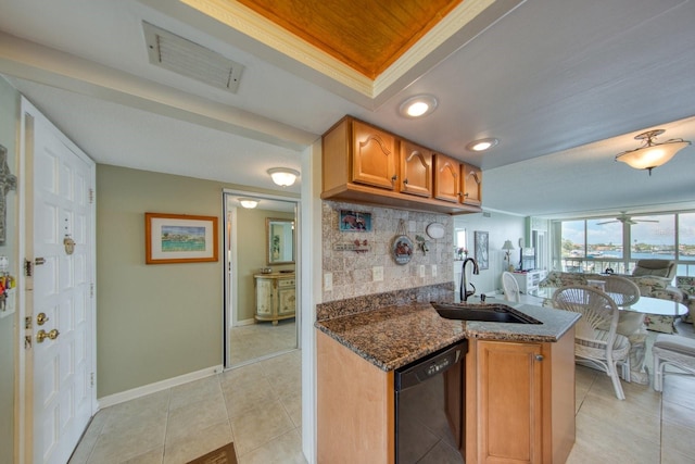 kitchen with sink, dark stone countertops, black dishwasher, decorative backsplash, and a raised ceiling