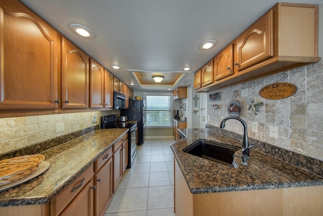 kitchen featuring sink, dark stone countertops, and black appliances