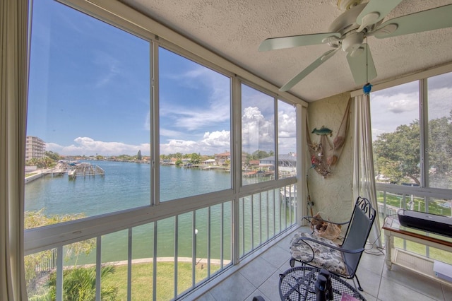 unfurnished sunroom featuring a water view, ceiling fan, and a wealth of natural light