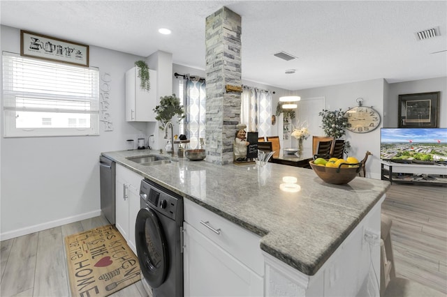 kitchen featuring a peninsula, washer / dryer, visible vents, and a sink