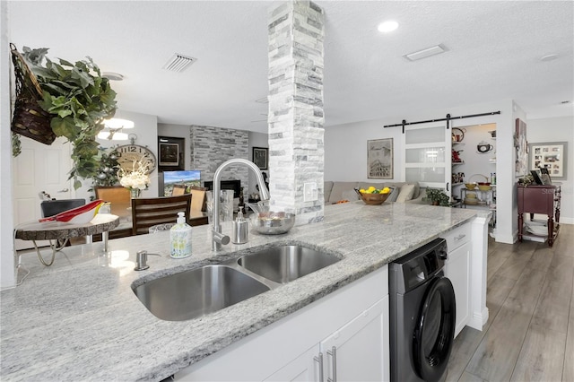 kitchen with open floor plan, washer / clothes dryer, a barn door, and a sink