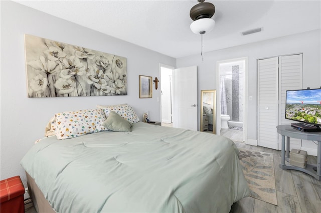 bedroom with ceiling fan, wood finished floors, visible vents, and connected bathroom