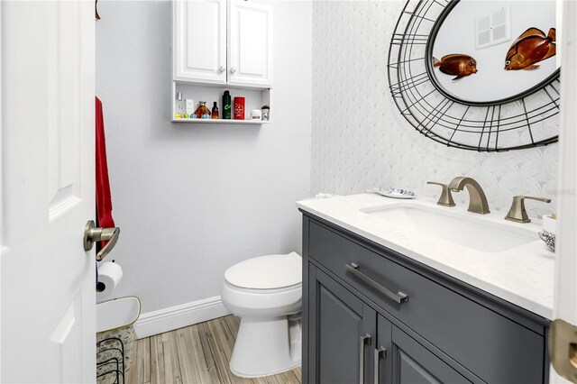 bathroom with baseboards, visible vents, toilet, wood finished floors, and vanity