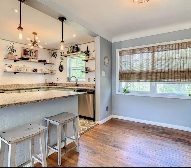 kitchen with stainless steel dishwasher, an inviting chandelier, light stone countertops, hanging light fixtures, and dark hardwood / wood-style flooring