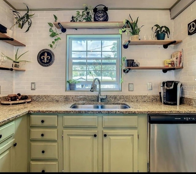 kitchen with stainless steel dishwasher, light stone counters, green cabinetry, and sink