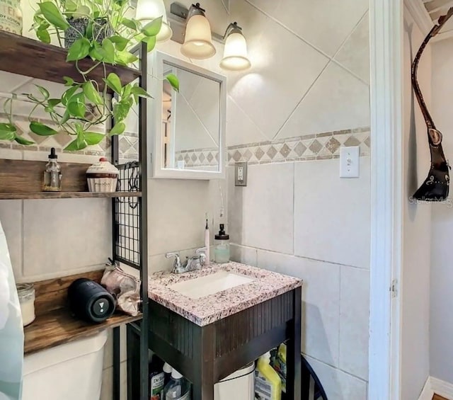 bathroom featuring tile walls, toilet, and vanity with extensive cabinet space