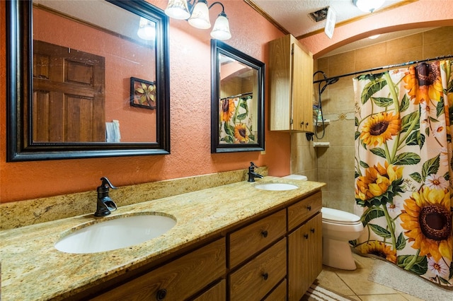 bathroom featuring double sink, a textured ceiling, tile flooring, toilet, and large vanity