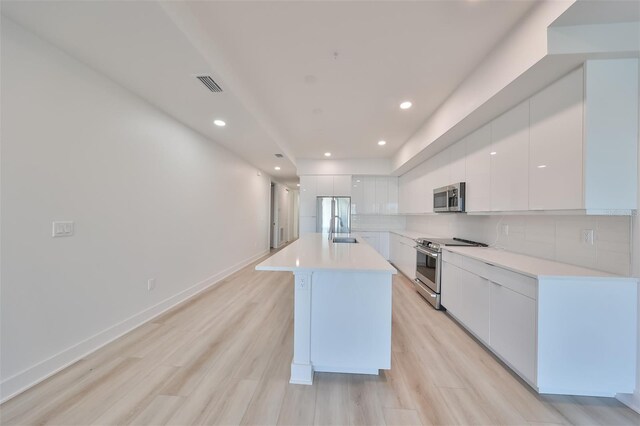 kitchen with visible vents, appliances with stainless steel finishes, white cabinets, a sink, and modern cabinets