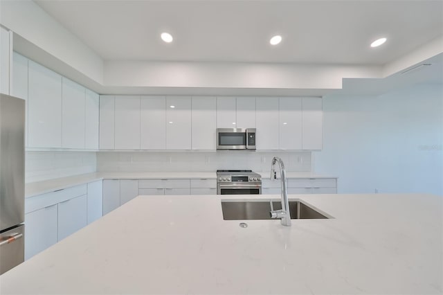 kitchen featuring stainless steel appliances, modern cabinets, a sink, and decorative backsplash