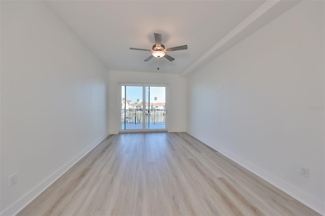 spare room featuring light wood finished floors, a ceiling fan, and baseboards