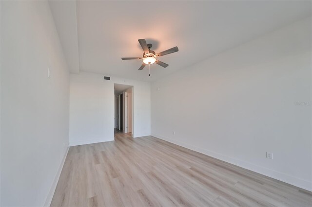 empty room featuring baseboards, ceiling fan, visible vents, and light wood finished floors