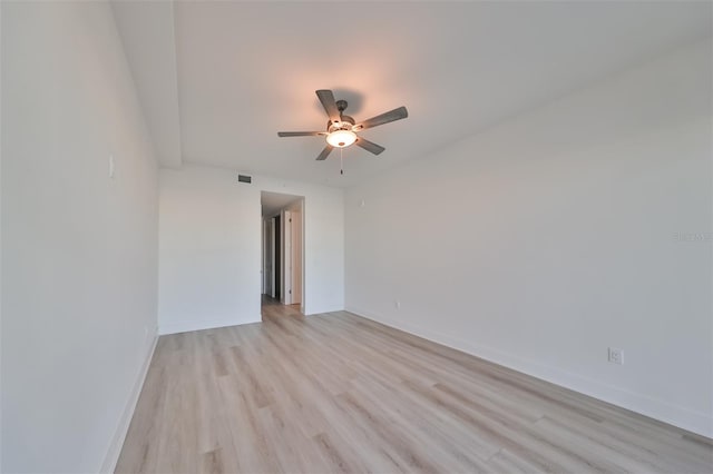 spare room with visible vents, light wood finished floors, a ceiling fan, and baseboards