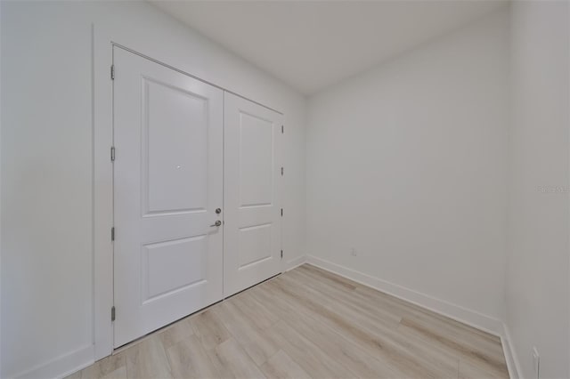 unfurnished room with light wood-type flooring and baseboards