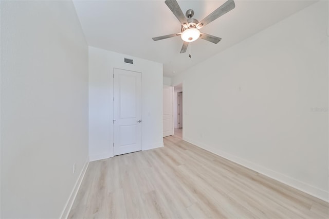 empty room featuring ceiling fan, light wood-style floors, visible vents, and baseboards