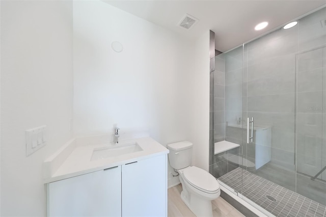 bathroom featuring visible vents, a shower stall, toilet, and vanity