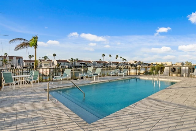 community pool with fence, a residential view, and a patio area
