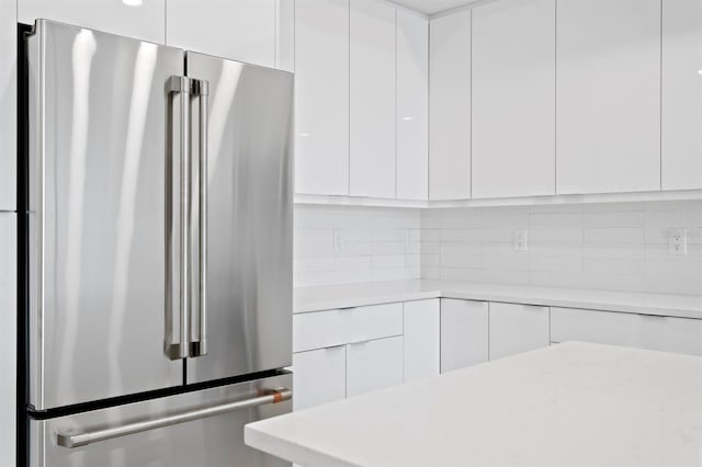 interior details featuring modern cabinets, high end fridge, light countertops, and white cabinets