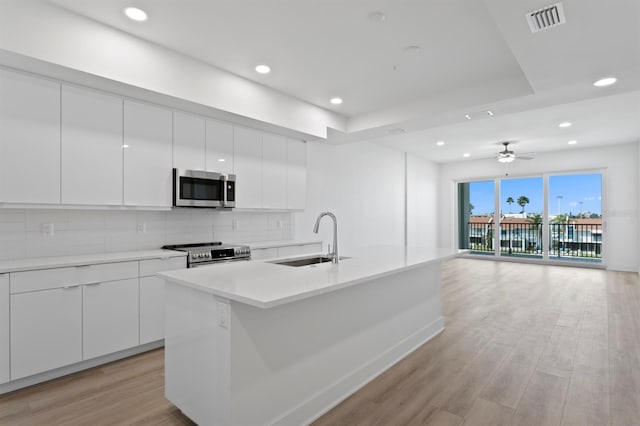 kitchen with decorative backsplash, visible vents, modern cabinets, stainless steel appliances, and a sink